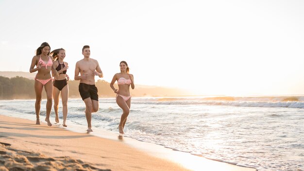 Full shot friends running together on shore