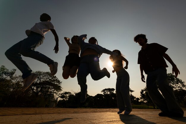 Full shot friends silhouettes jumping at sunset