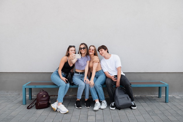 Free photo full shot friends sitting on bench