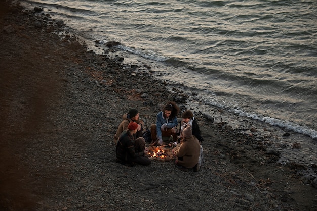 Full shot friends sitting by the fire