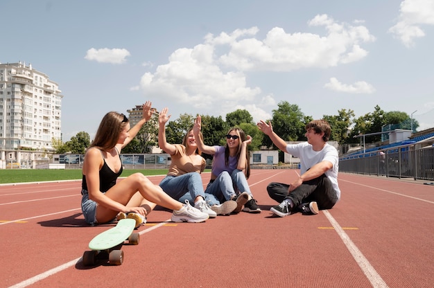 Free photo full shot friends sitting on field