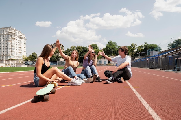 Free photo full shot friends sitting on field