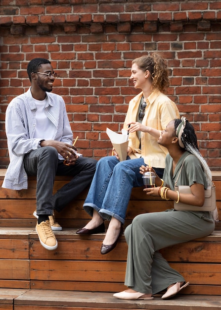 Full shot friends sitting outdoors