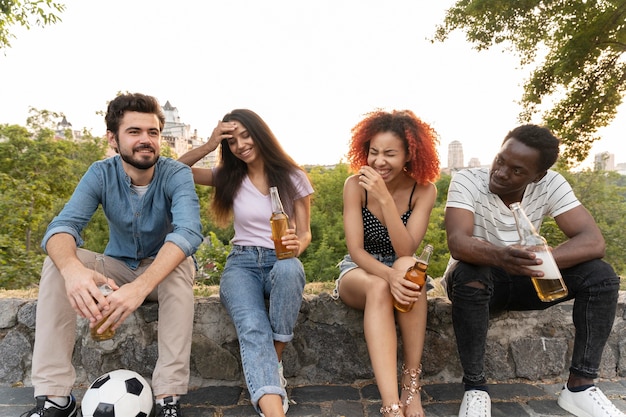 Free photo full shot friends sitting outdoors