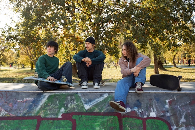 Free photo full shot friends sitting in skatepark