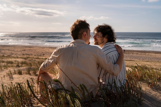 Foto gratuita coppia gay a figura intera in spiaggia