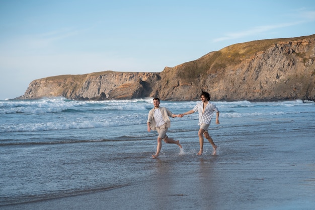 Полный снимок геев, держащихся за руки на пляже