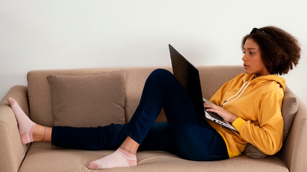 Full shot girl on couch with laptop