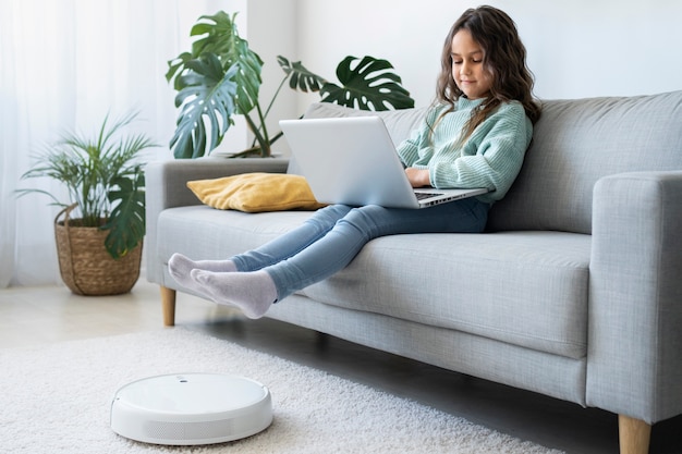 Free photo full shot girl on couch with laptop