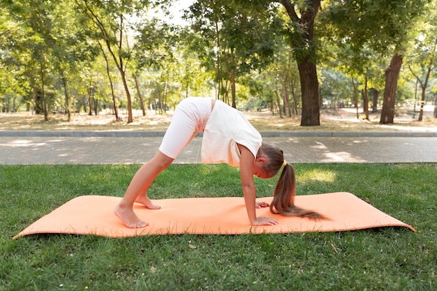 Full shot girl doing yoga on mat