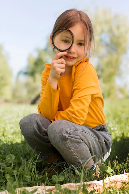 Free photo full shot girl holding magnigying glass