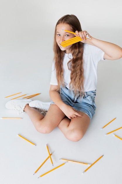 Free photo full shot girl holding pencils