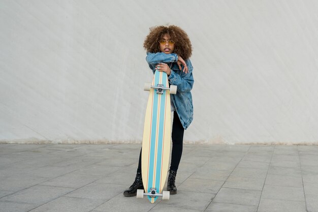 Free photo full shot girl holding skateboard