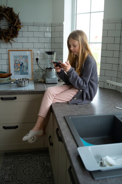 Full shot girl holding smartphone