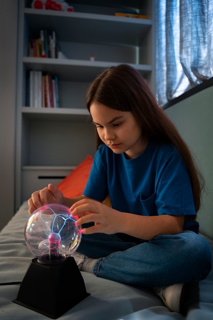 Full shot girl interacting with a plasma ball