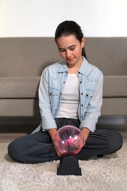 Free photo full shot girl interacting with a plasma ball