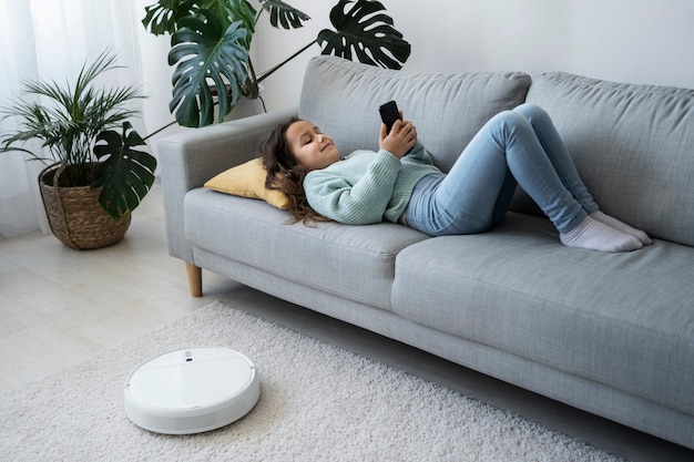 Free photo full shot girl laying on couch with smartphone