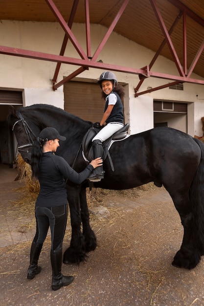 Foto gratuita ragazza a tutto campo che impara a cavalcare