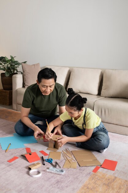 段ボールの家を作るフルショットの女の子と男