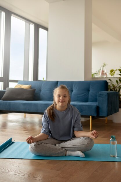 Full shot girl meditating on mat