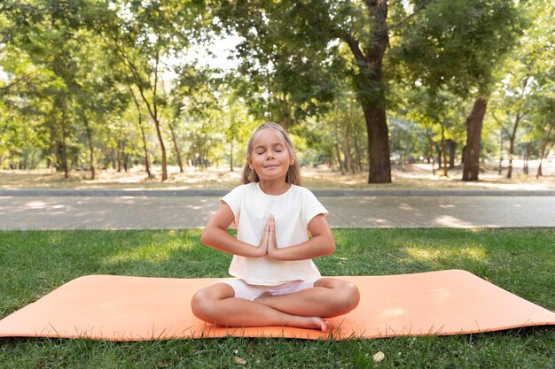 Full shot girl meditating on yoga mat