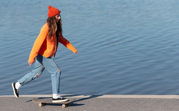 Бесплатное фото Девушка в полный рост на коньках у озера