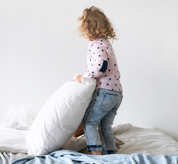 Free Photo full shot girl playing in bed with pillow 
