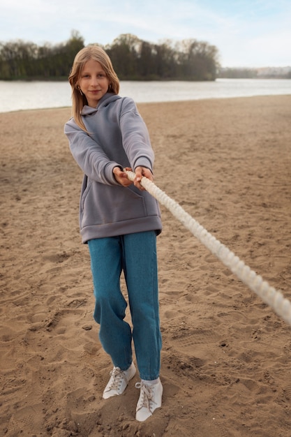 Free photo full shot girl playing tug-of-war on the beach