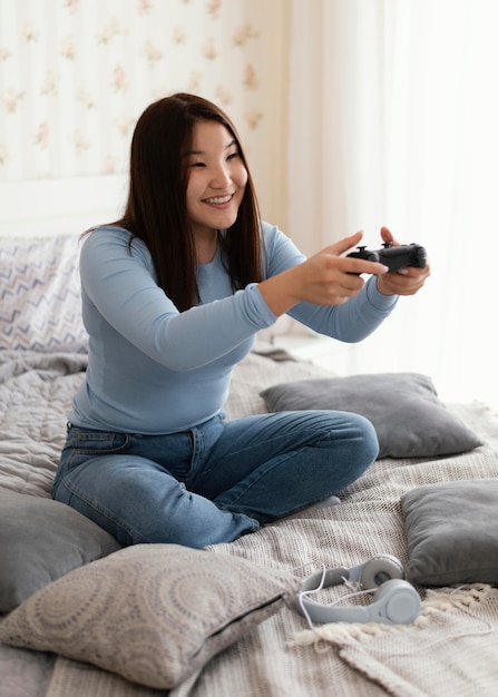 침대에서 비디오 게임을하는 전체 샷 소녀