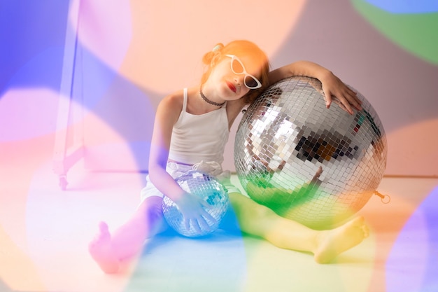Full shot girl posing with disco ball and sunglasses