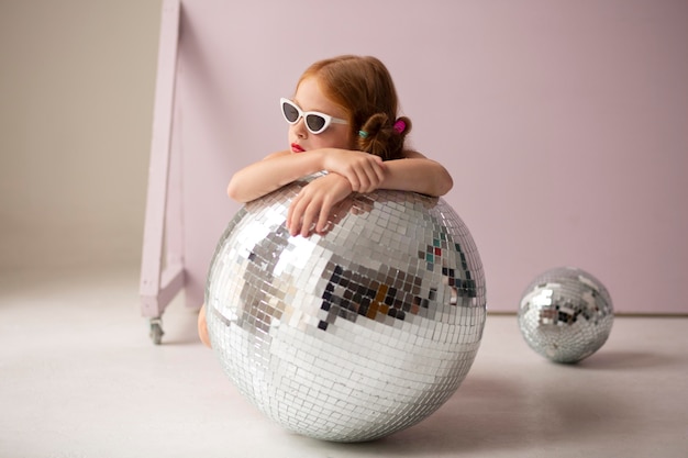 Full shot girl posing with disco ball