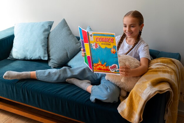 Free photo full shot girl reading comics indoors