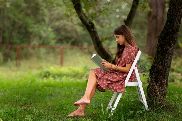 Полный снимок девушки, читающей на природе