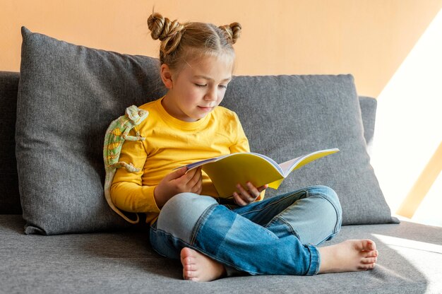 Full shot girl reading with chameleon