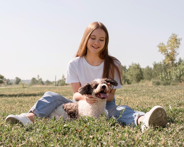 Полный выстрел девушка сидит на траве с собакой