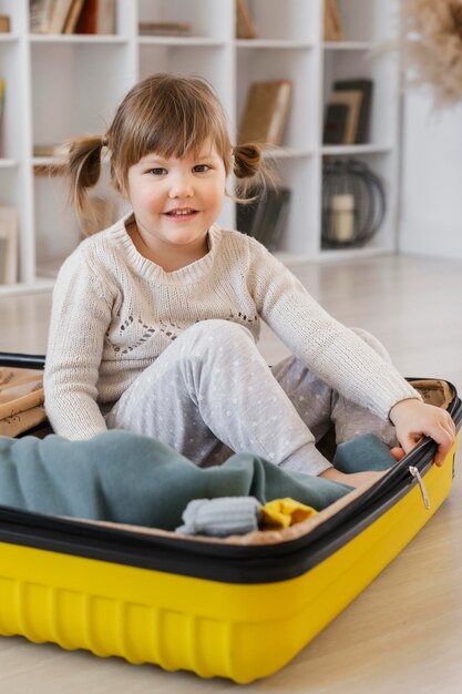 Full shot girl sitting in luggage
