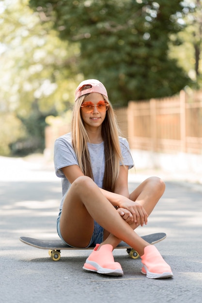 Полный выстрел девушка сидит на скейтборде