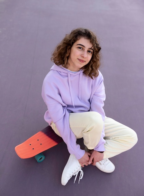 Foto gratuita ragazza del colpo pieno che si siede sullo skateboard