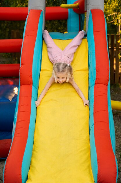 Full shot girl sliding on bounce house