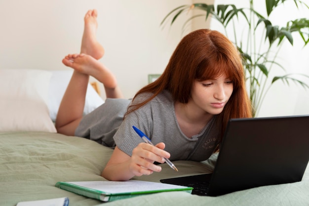 Full shot girl studying with laptop