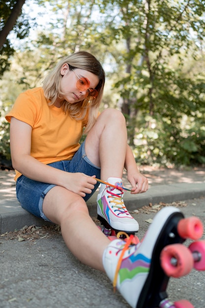 Бесплатное фото Девушка в полный рост завязывает шнурки для роликовых коньков