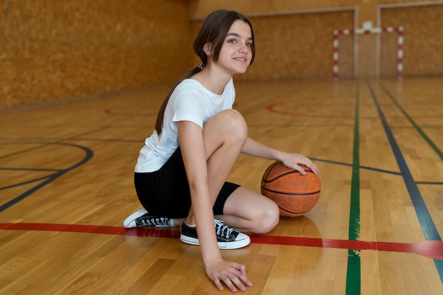 ジムでバスケットボールのフルショットの女の子