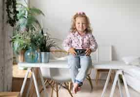 Free photo full shot girl with camera sitting on a table