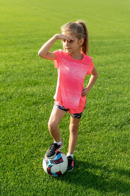 ピンクのtシャツとボールを持つ少女の完全なショット