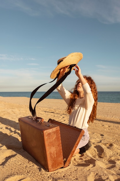 Полный снимок девушка с чемоданом и шляпой