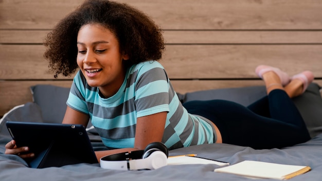 Full shot girl with tablet in bed