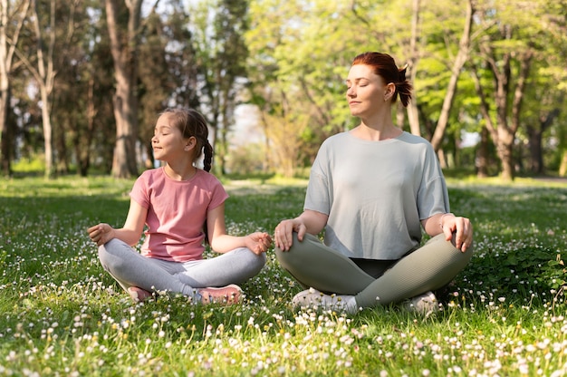 Full shot girl and woman sitting on grass