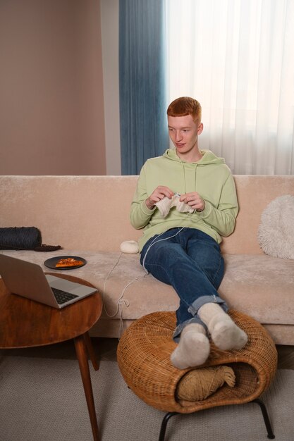 Full shot guy knitting at home