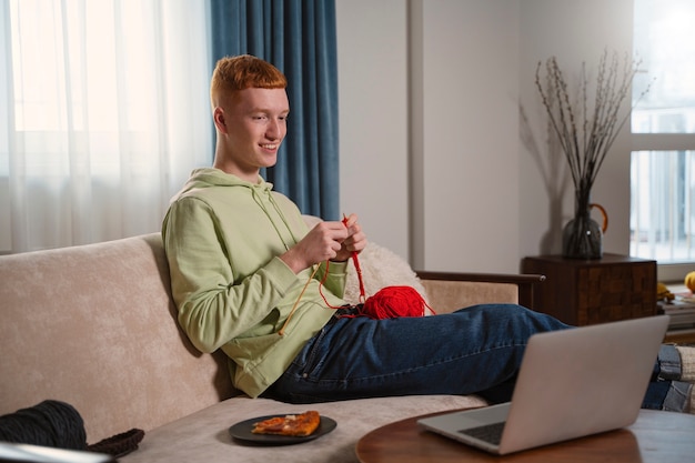 Full shot guy knitting with red yarn