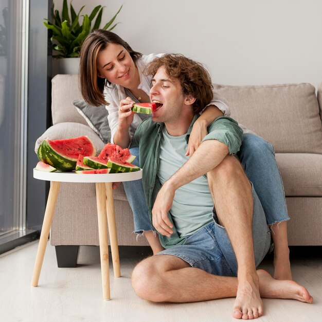 Full shot happy couple eating watermelon